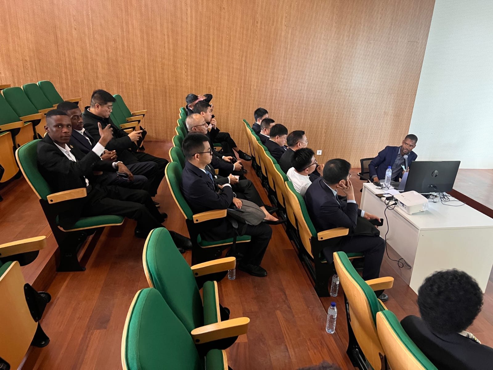 Delegação do Governo Chinês reunida em sessão de trabalho em auditório, acompanhada por interpretação da Gemini Multiservice